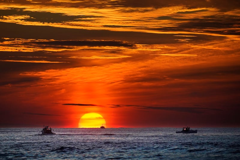 O sol nasce sobre barcos de pesca no Oceano Atlântico, 8 de setembro de 2022, perto de Kennebunkport, Maine.