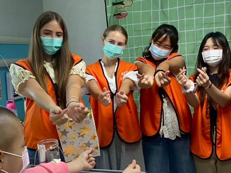 Jovens adultos de A Igreja de Jesus Cristo dos Santos dos Últimos Dias compartilham gestos de sinal de coração com um jovem paciente com câncer em um hospital infantil na cidade de Changhua, Taiwan. Os jovens adultos visitam o hospital duas vezes por mês para compartilharem aulas de musicoterapia e arteterapia.