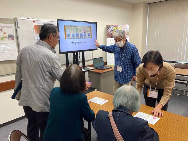 Indivíduos aprendem como usar os aplicativos FamilySearch em seus smartphones durante uma feira de história da família de Kagoshima, Japão, 23 de fevereiro de 2026.
