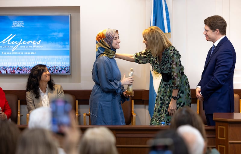 Elder Alan R. Walker e Sister Inés Walker sorriem para Sümeyra Nur Korkut durante a cerimônia "Women who Illuminate" em Buenos Aires, Argentina, 19 de março de 2026.
