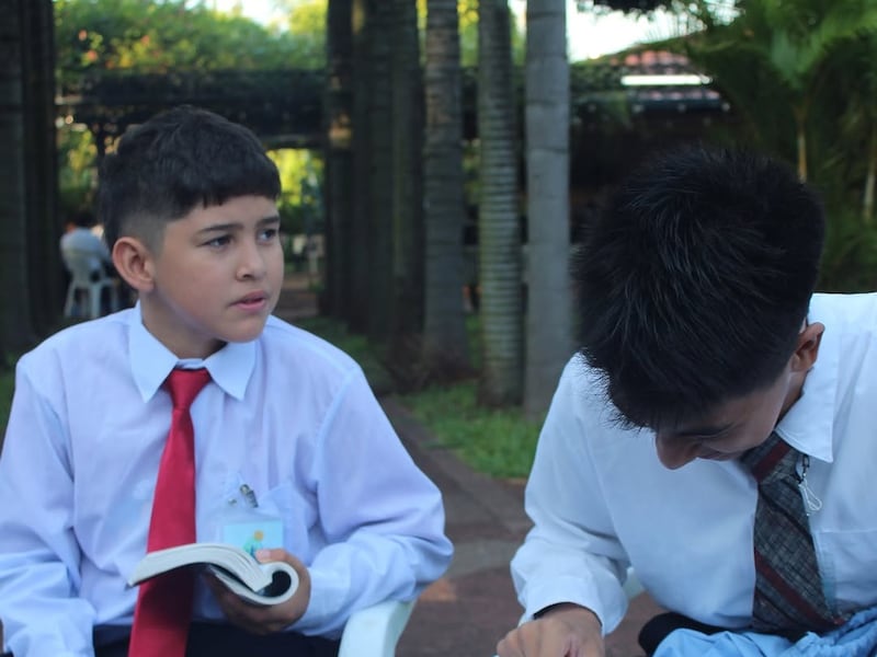 Dois jovens estudam as escrituras em uma conferência Para o Vigor da Juventude no Paraguai em janeiro de 2026.