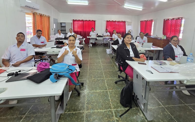 Os 14 alunos da turma inaugural do programa de Bacharelado em Saúde Oral sorrirem na sala de aula de odontologia no Hospital Viola em Nukuʻalofa, Tonga, em março de 2026.