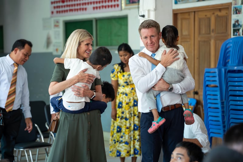 O Presidente Geral dos Rapazes Timothy L. Farnes, à direita, e sua esposa, irmã Linsey Farnes, seguram crianças pequenas durante visita ao Centro Nacional para Bebês e Crianças no Camboja em 23 de maio de 2026.