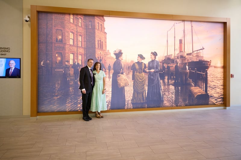 Novos líderes de missão tiram uma foto perto do mural das primeiras irmãs missionárias solteiras no Centro de Treinamento Missionário de Provo.