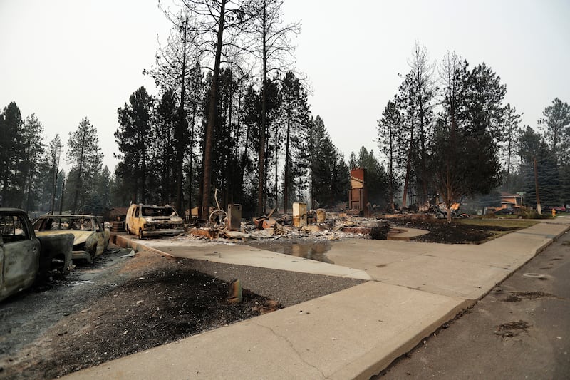 Detritos estão espalhados ao redor de estruturas queimadas após um incêndio florestal, domingo, 2 de agosto de 2026, em Spokane, Washington.