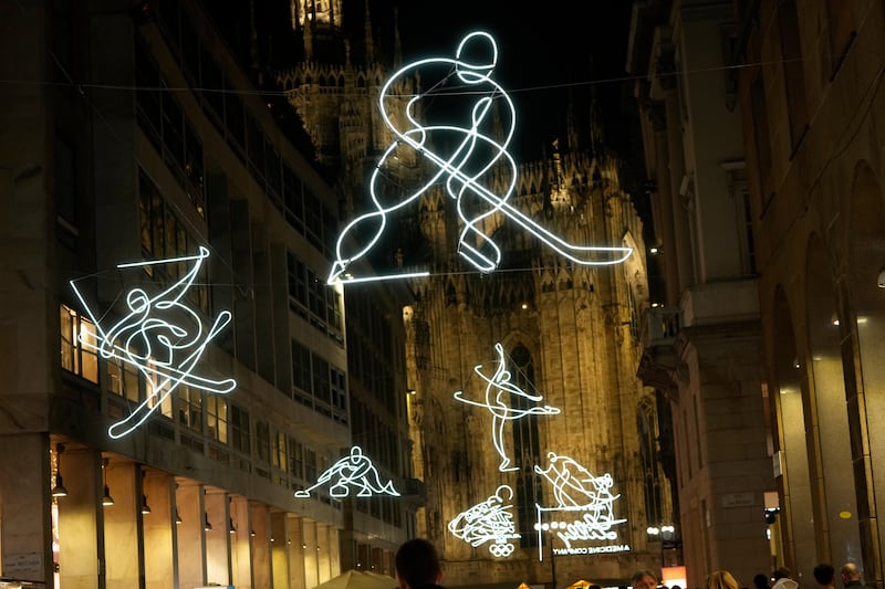 Formas em néon de um jogador de hóquei, esquiador, patinador no gelo, jogador de curling e mais estão penduradas ao lado da catedral gótica Duomo para os próximos Jogos Olímpicos de Inverno de Milan-Cortina em Milão, Itália, sábado, 27 de dezembro de 2025.