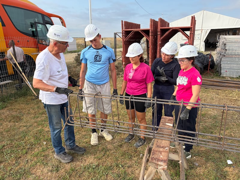 Élder John Dickson, um missionário humanitário em tempo integral de A Igreja de Jesus Cristo dos Santos dos Últimos Dias, trabalha com jovens adultos preparando aço reforçado durante um projeto de serviço da Habitat for Humanity Romania em Berceni, Romênia, em agosto de 2026.