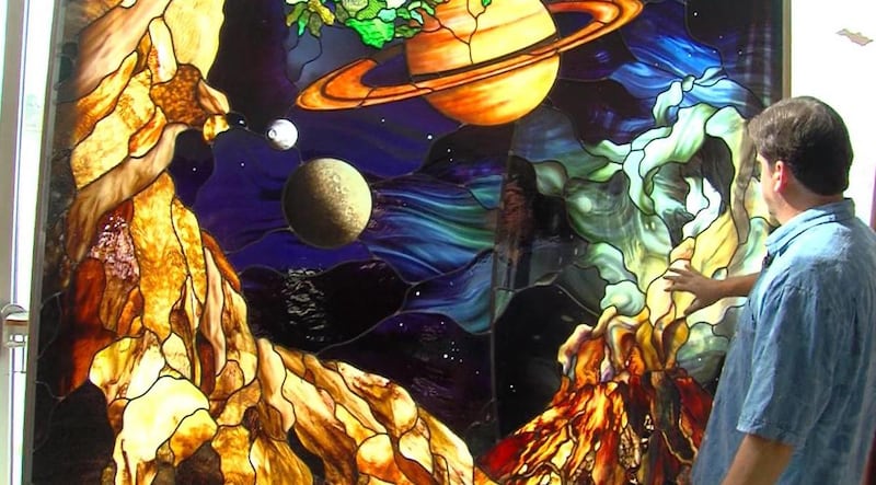O artista de vitral Tom Holdman mostra um dos painéis de vidro que seu estúdio criou para a celebração do 75º aniversário da Utah Valley University em 2017.