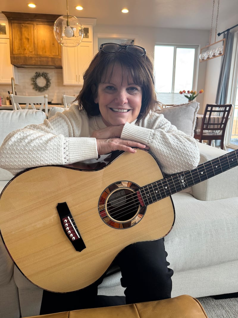 Shawna Edwards — compositora de "Because", uma nova adição a Hymns—For Home and Church — posa para uma foto com um violão em Lehi, Utah, janeiro de 2025.