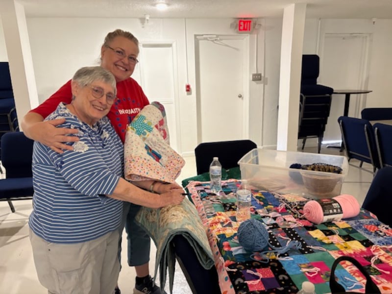 Susan Whitfield, à esquerda, e Grace Ann Skousen, à direita, posam para uma foto com colchas feitas durante o Dia de Serviço de 11/9 da Estaca Stapley Gilbert Arizona em 13 de setembro de 2025, em Gilbert, Arizona. As colchas foram entregues à Gathering Humanity para serem doadas a refugiados.