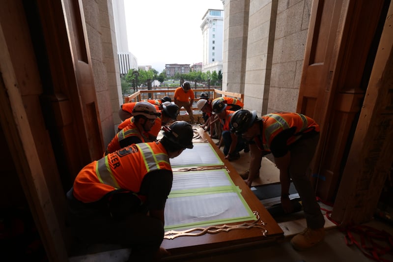 Trabalhadores preparam as portas leste do Templo de Salt Lake para serem içadas e colocadas no lugar na terça-feira, 23 de junho de 2026.