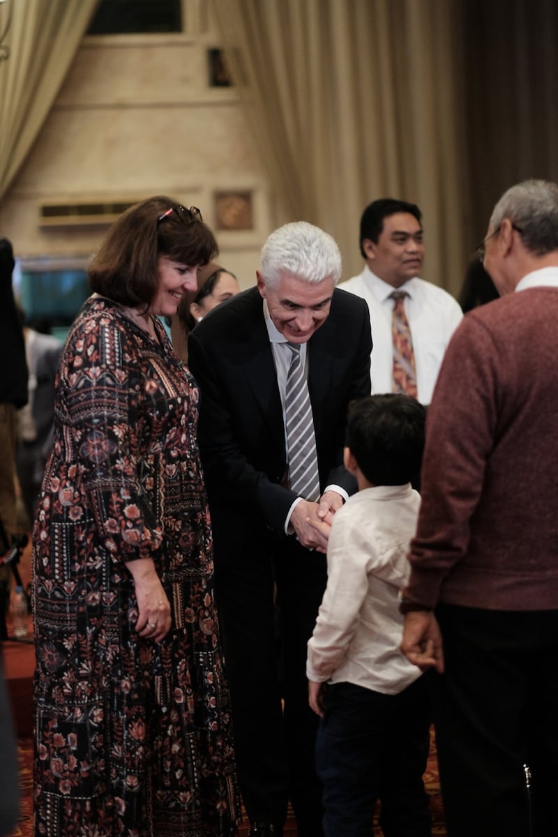 Elder Gérald Caussé do Quórum dos Doze Apóstolos e a irmã Valérie Caussé cumprimentam um jovem membro antes do devocional de membros em Jacarta, Indonésia, no dia 21 de abril de 2026.