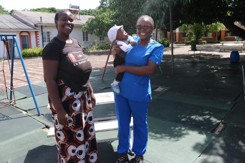 Um bebê de um ano se reúne com um membro da equipe da NICU fora do Hospital Geral Lewanika em Mongu, Zâmbia. O bebê Samuel nasceu prematuro em dezembro de 2024.