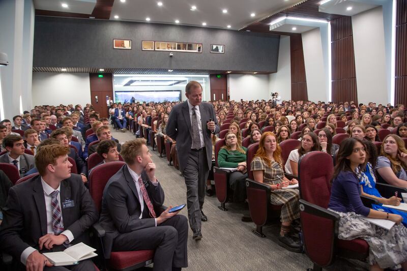 Elder Gary E. Stevenson do Quórum dos Doze Apóstolos caminha pelo corredor enquanto fala a mais de 700 missionários no Centro de Treinamento Missionário.