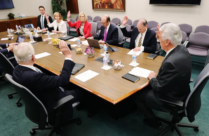 Cinco membros do Conselho Executivo Missionário sentam-se à mesa e levantam as mãos em apoio a um item durante uma reunião do Conselho Executivo Missionário no Edifício da Sede da Igreja em Salt Lake City na quarta-feira, 26 de maio de 2021.