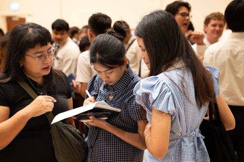 Supavadee Kasinsri e sua filha fazem anotações para navegar pelos estandes da feira de educação da Área da Ásia em Bangkok, Tailândia, em 19 de outubro de 2025.