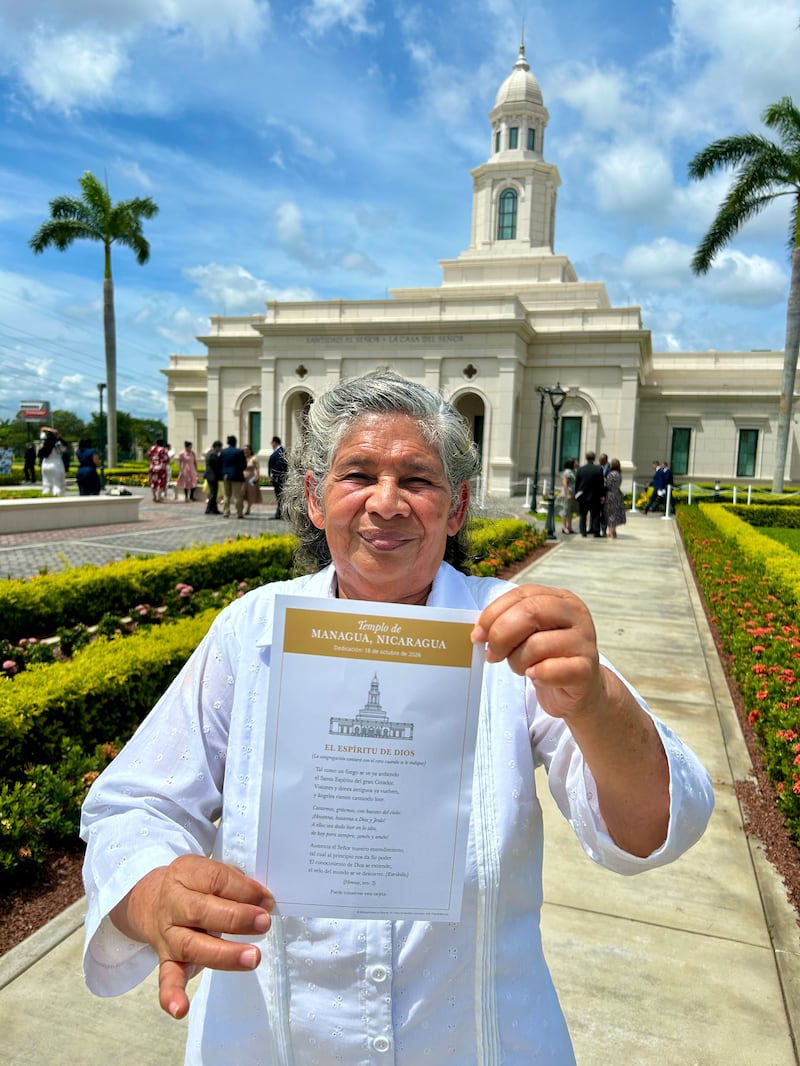 Betty Antonia Castro Torres segura um cartão com as palavras do hino "The Spirit of God Like a Fire is Burning" fora do Templo de Managua Nicarágua após a dedicação em Managua, Nicarágua, no domingo, 18 de outubro de 2026.