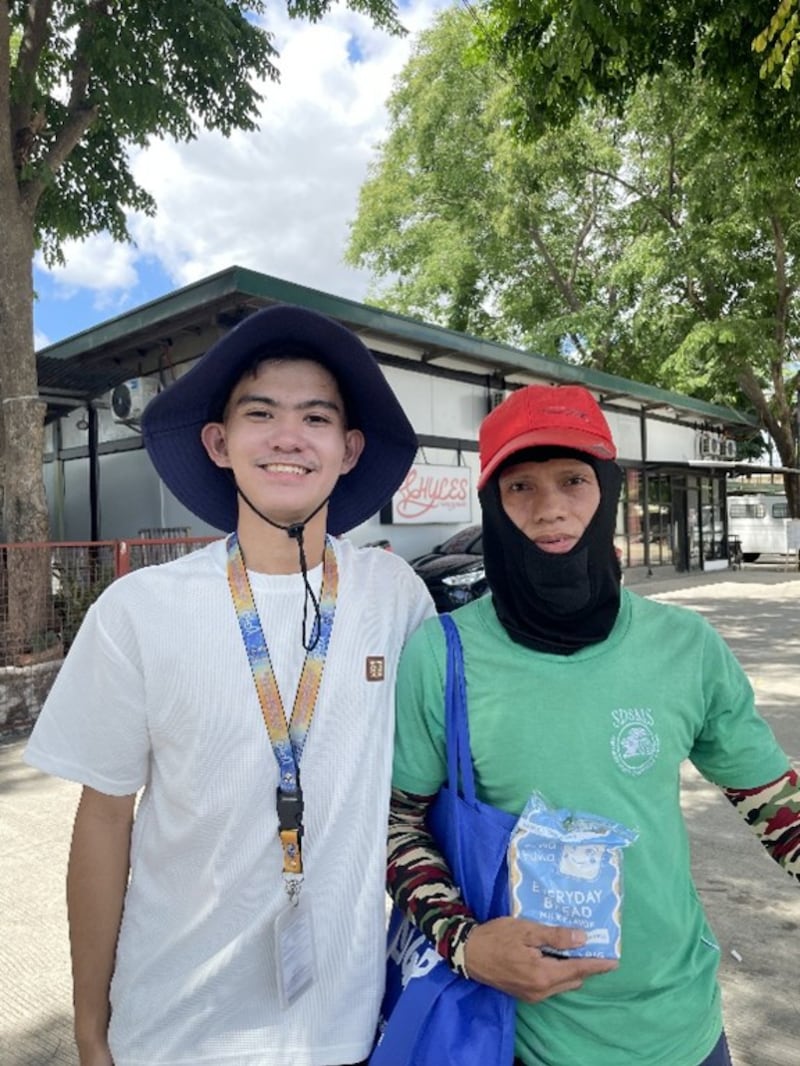 Rodolfo Gallinero III, à esquerda, posa para uma foto com o destinatário de um kit de cuidados montado por jovens estudantes em Santo Tomas, Filipinas, em 1º de maio de 2026.
