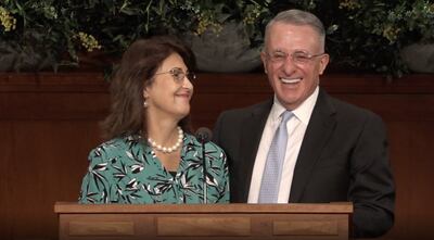 Élder Ulisses Soares e a irmã Rosana Soares sorriem juntos ao púlpito durante a transmissão de um devocional mundial para missionários de tempo integral no dia 18 de março de 2021.