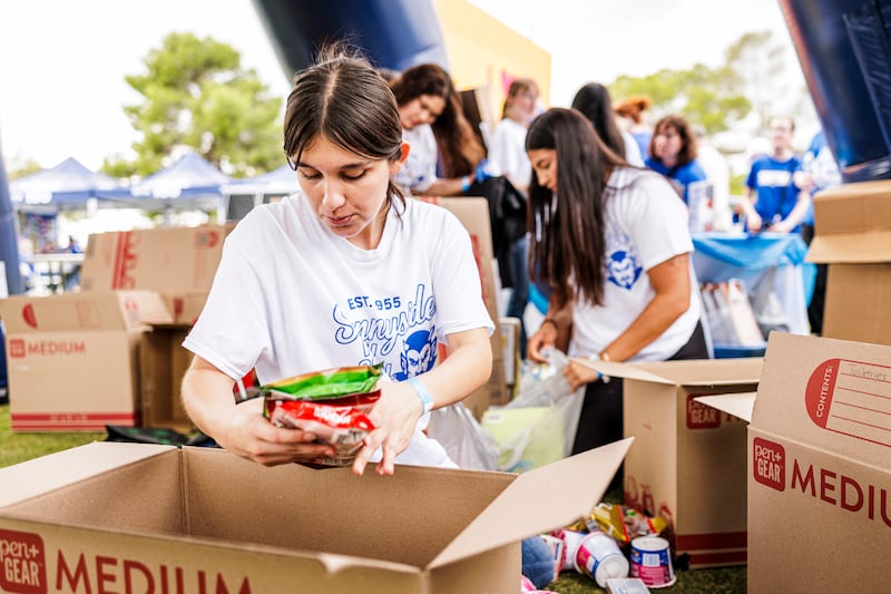 Voluntários e funcionários da Fundação Sunnyside selecionam alimentos doados por ex-alunos e fãs da BYU antes do jogo BYU-Arizona em Tucson, Arizona, no sábado, 11 de outubro de 2025.