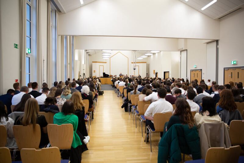 Participantes ouvem durante um devocional de 22 de abril de 2022 em Friedrichsdorf, Alemanha, que foi transmitido ao vivo para os santos dos últimos dias falantes de alemão na Áustria, Alemanha e Suíça.