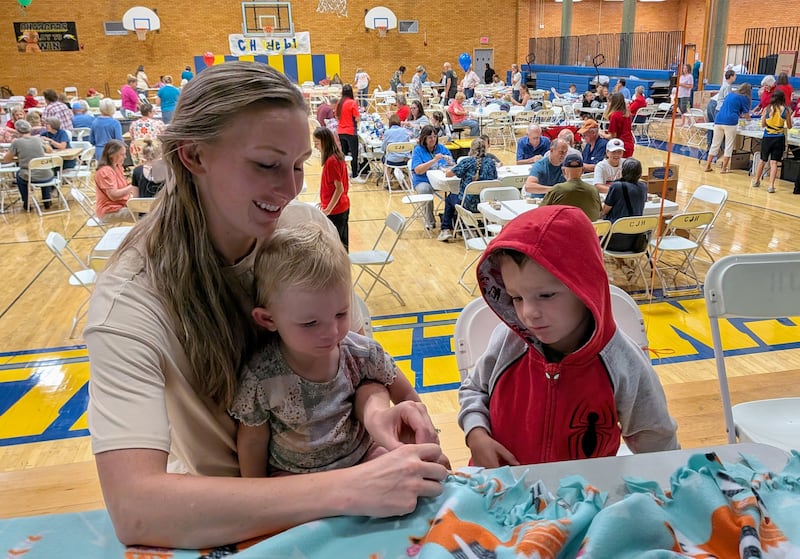 Tawnya Turner mostra a seus filhos como amarrar um cobertor de fleece como parte de um evento do Dia Nacional de Serviço e Lembrança em Centerville, Utah, no sábado, 12 de setembro de 2026.