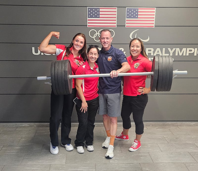 O aposentado Major da Marinha dos EUA Yen Soto, à extrema direita, posa para uma foto com os treinadores Brad Johnson e Lydia Figary e com a colega de equipe Victoria Rodriguez no centro de treinamento dos Jogos dos Guerreiros de 2025 em Colorado Springs, Colorado.