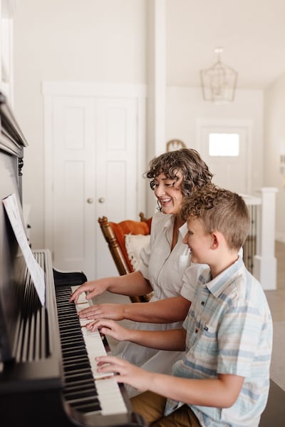 Angie Killian, compositora de "Anytime, anywhere", toca piano com seu filho Carter Killian em sua casa de Salem, Utah, 2024.