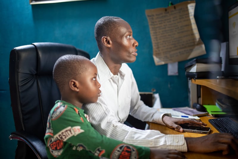 O estudante do BYU–Pathway Worldwide, Success Levi, e seu filho, Success Levi Jr., sentam-se juntos em frente a um computador em Lagos, Nigéria, em janeiro de 2025.