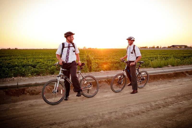 Dois missionários de A Igreja de Jesus Cristo dos Santos dos Últimos Dias andam de bicicleta em uma zona rural.