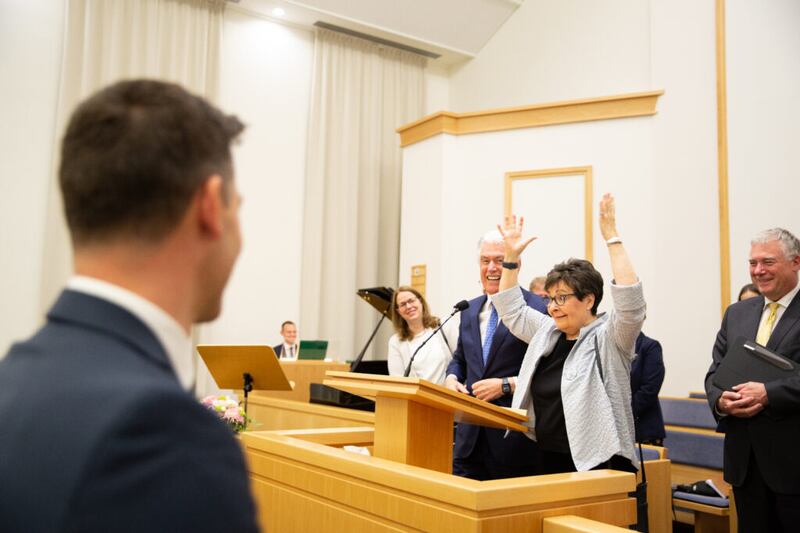 A irmã Harriet Uchtdorf, esposa de Élder Dieter F. Uchtdorf, levanta os braços para o alto para fazer um coração com as mãos e mostrar seu amor, após um devocional de 22 de abril de 2022 em Friedrichsdorf, Alemanha, que foi transmitido ao vivo para os santos dos últimos dias falantes de alemão na Áustria, Alemanha e Suíça.