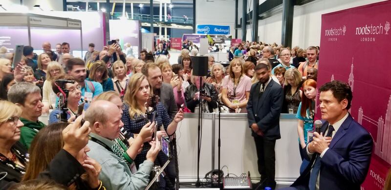 Artista Santo dos Últimos Dias, Donny Osmond, à direita, encontra com representantes da mídia na RootsTech Londres no dia 26 de outubro, 2019, com uma longa fila de participantes esperando para encontrá-lo numa sessão de encontrar e cumprimentar.