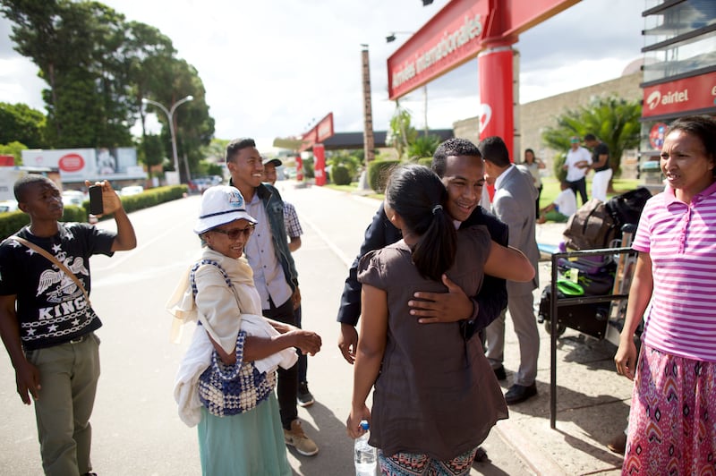 Um missionário que retorna cumprimenta amigos e familiares fora do aeroporto em Madagascar em 2026.
