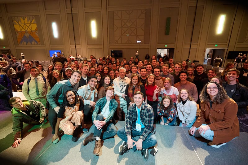 Élder Gerrit W. Gong, do Quórum dos Doze Apóstolos, e a irmã Susan Gong tiram uma foto com um grupo de jovens adultos na festa pós-evento da RootsTech na sexta-feira, 3 de março de 2023.