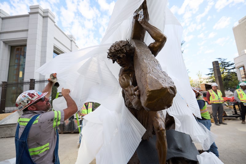 Membros da equipe instalam a estátua \"Jesus Christ Carrying the Cross\", criada por Michael Hall, logo ao sul do Templo de Salt Lake na quarta-feira, 17 de setembro de 2025.