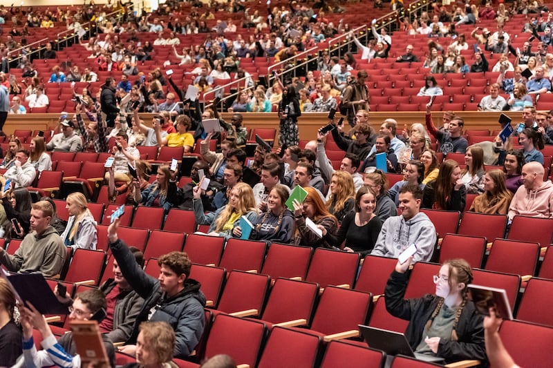 Alunos da BYU-Idaho erguem seus cadernos e escrituras, em papel ou eletrônicos, no início do primeiro devocional do semestre, no I-Center em Rexburg, Idaho, na terça-feira, 18 de abril. Esta tradição permite que os alunos mostrem ao orador que estão prontos para aprender.