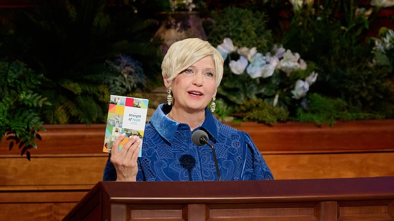 A Presidente Geral das Moças, Emily Belle Freeman, segura uma cópia de "For the Strength of Youth" enquanto ela fala durante a sessão da manhã de domingo da 196ª Conferência Geral Anual de A Igreja de Jesus Cristo dos Santos dos Últimos Dias no Centro de Conferências em Salt Lake City em 5 de abril de 2026.