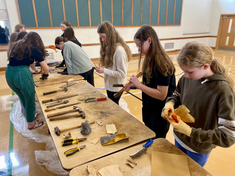 Jovens da Estaca Northampton Inglaterra reformam ferramentas antigas sobre uma mesa para doar à organização chamada Tools with a Mission em abril de 2024.