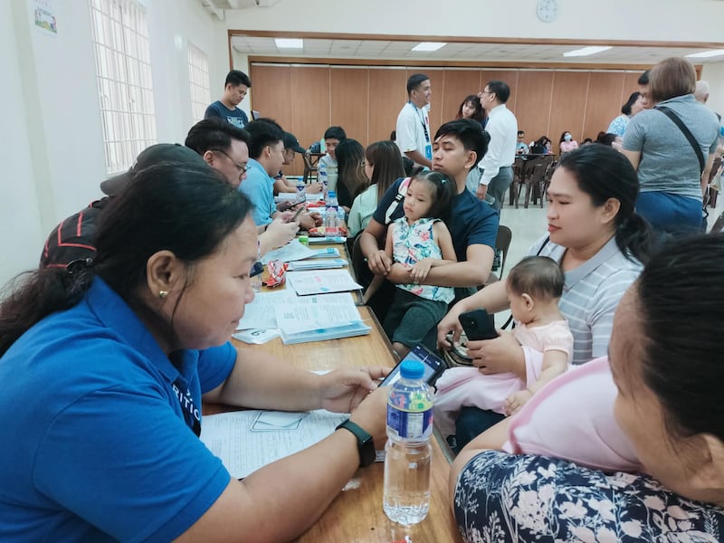 Pais seguram seus filhos no Pasay Philippines Stake Center durante uma triagem de nutrição infantil em 18 de abril de 2026.